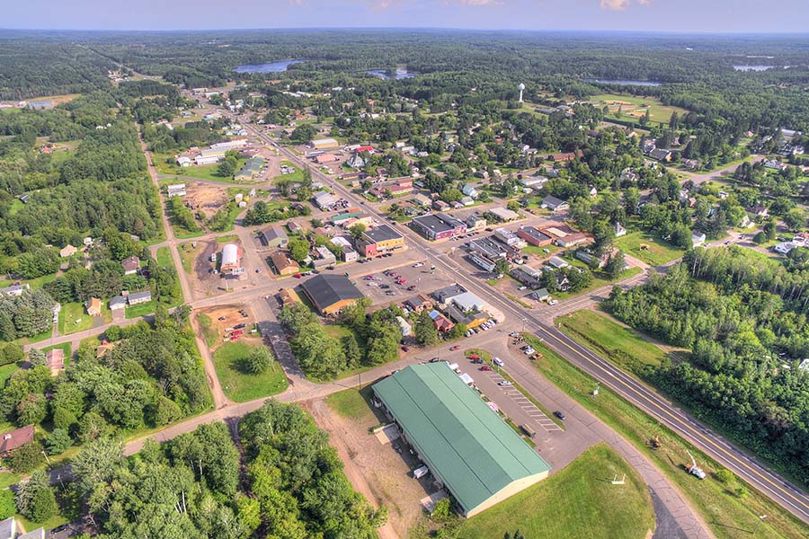 Cross Plains, WI - Aerial View of a Wisconsin Town Displaying Many Buildings, Homes and Trees With a Creek in the Distance